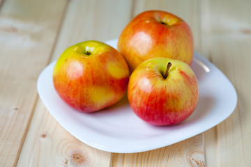 Naklejka na ściany i meble Свежие яблоки в блюде на деревянном столе
