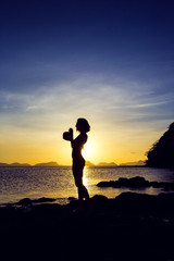 Girl with coconut at sunset enjoying the sunset