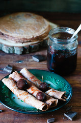 Chocolate crepe with jam on dark wooden table
