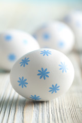 Obraz na płótnie Canvas White eggs with blue pattern on wooden background