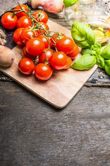 Fresh cherry tomatoes with basil and olive oil on rustic wooden background