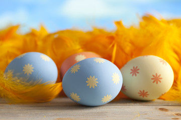 Colorful Easter eggs and feathers on blue background