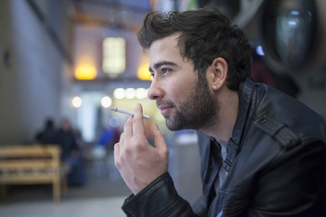 Handsome stylish young man smoking outside