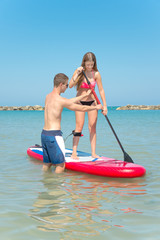 Fototapeta na wymiar Boy and girl on stand up paddle