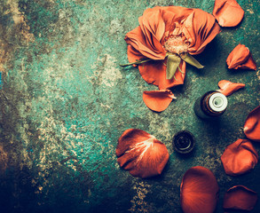 Roses flowers with petal and essential oil on rustic vintage background, top view , place for text. Aromatherapy and cosmetic concept