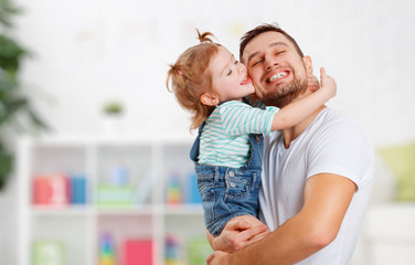 happy family and father's day. daughter kissing and hugging dad