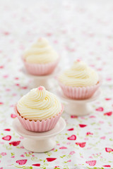 Three vanilla cupcakes with buttercream swirl topping on mini cake stands