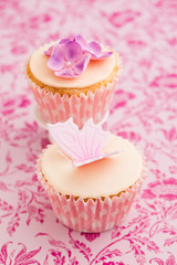 Cupcakes decorated with pink sugar flowers and a sugar butterfly