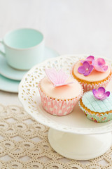 Cupcakes decorated with pink sugar flowers and a sugar butterfly