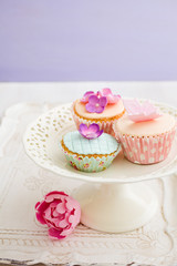 Cupcakes decorated with pink sugar flowers and a sugar butterfly