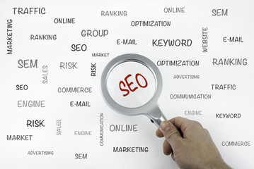 Sheet with text and magnifier enlarging word SEO