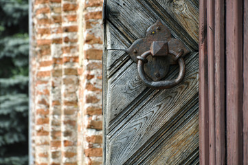 Ancient metal rusty door handle in the form of a ring on the background of a wooden door