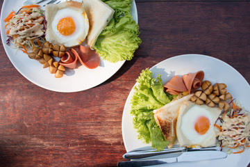 English breakfast with eggs, ham, sausages, toasts and salad