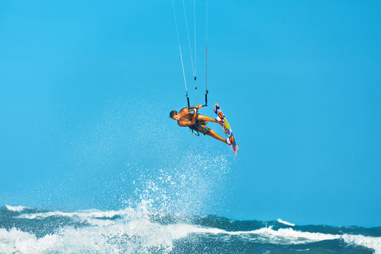 Recreational Water Sports Action. Healthy Man ( Surfer ) Kiteboarding ( Kite Surfing ) On Waves In Sea, Ocean. Extreme Sport. Summer Fun, Vacation. Active Lifestyle. Leisure Sporting Activity. Hobby