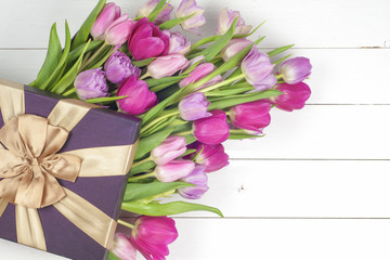 Purple tulips and gift box over wooden table. Top view with copy space