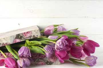 Purple tulips and gift box over wooden table. 