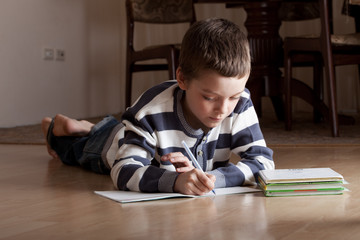 Boy does lessons lying on the floor