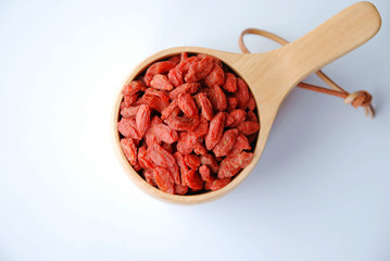 healthy dried goji berries in a wooden cup in white background