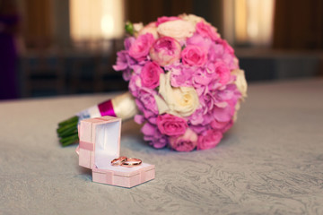 gold wedding rings and pink bridal bouquet