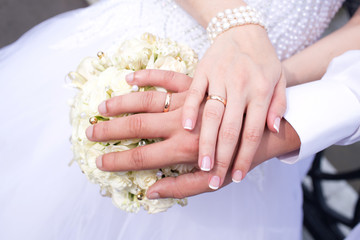Hands of the groom and bride with rings and bridal bouquet