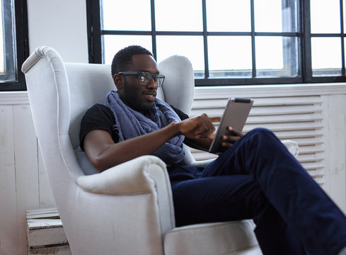 A blackman sitting on the chair and working with computer.