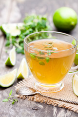 Green  tea with thyme and lime on rustic wooden background