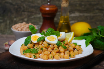 Mediterranean cuisine. Dish of chickpeas with mint, olive oil and lemon sauce on a wooden background