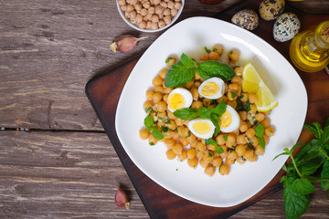 Mediterranean cuisine. Dish of chickpeas with mint, olive oil and lemon sauce on a wooden background