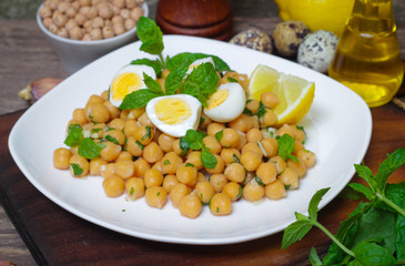 Mediterranean cuisine. Dish of chickpeas with mint, olive oil and lemon sauce on a wooden background