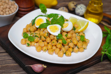 Mediterranean cuisine. Dish of chickpeas with mint, olive oil and lemon sauce on a wooden background