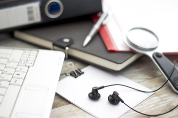 Office workplace with laptop, magnifying and headphone on wood table
