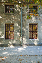 Fototapeta na wymiar Old stone wall with four windows in the sun