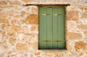 Green wooden window in stone wall
