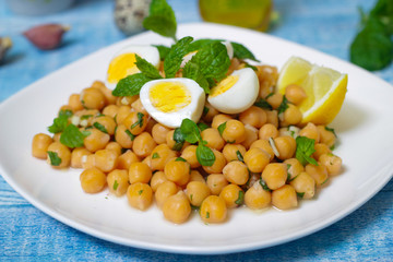 Mediterranean cuisine. Dish of chickpeas with mint, olive oil and lemon sauce on a wooden background