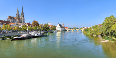 Fototapeta premium Panoramic view on Danube river in Regensburg with Regensburg Cathedral, Old steamship, Tower of Town Hall, Salt House and Stone Bridge, Germany