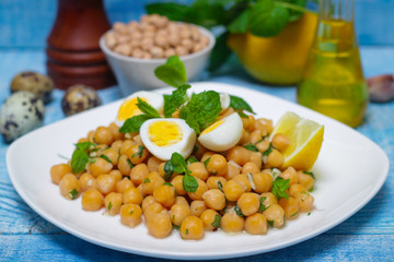 Mediterranean cuisine. Dish of chickpeas with mint, olive oil and lemon sauce on a wooden background