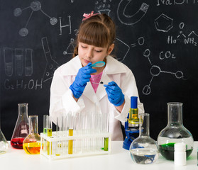 little schoolgirl looking through magnifier on reagents
