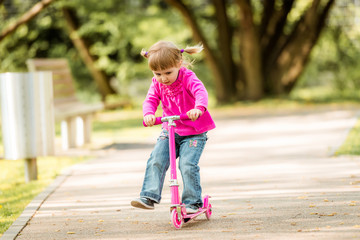 little Two years old girl riding her scooter