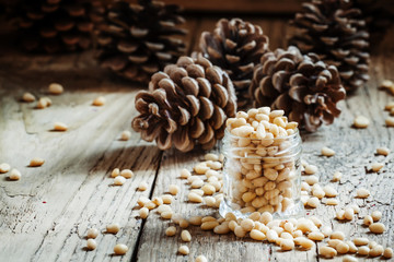 Cedar nuts in a jar on a wooden table, selective focus