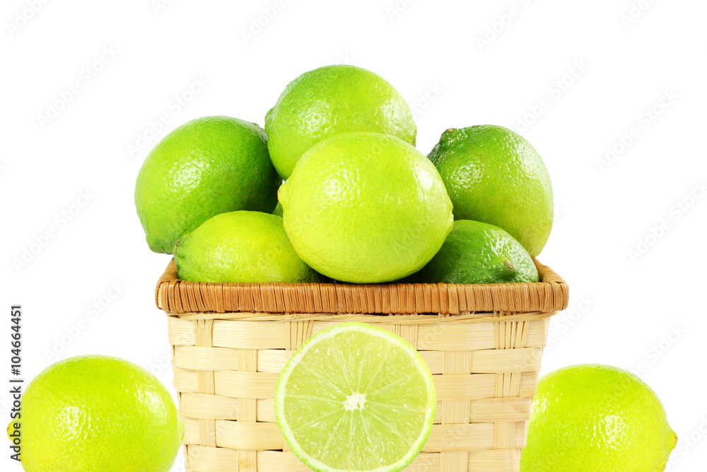 Wall mural fresh lemon lime citrus fruit in bamboo basket in white background