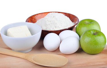 Fototapeta na wymiar Butter, flour, eggs and apples on a wooden board