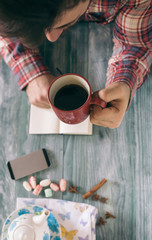 Man reading a book and writing notes on wooden table on sunset.