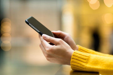 Womens hand using mobile phone on the bokeh background