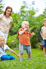 Fototapeta na wymiar Baby beim Laufen lernen im Kreis der Familie