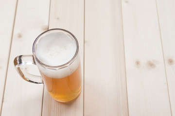 Mug of unfiltered beer on the wooden table. Top down viewpoint.  