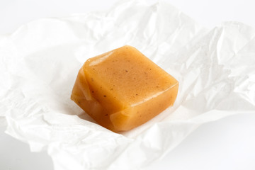 SIngle luxury unwrapped caramel toffee on white wrapper in persp