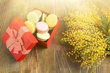 Some macaroons in gift box and mimosa with sun flare