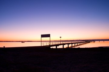 Fototapeta premium Morning in harbor. Tourists pier above sea. Sunny clear blue sky, smooth water level