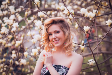 Beauty smiling woman near white magnolia