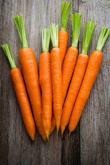 Fresh carrots bunch on rustic wooden background.